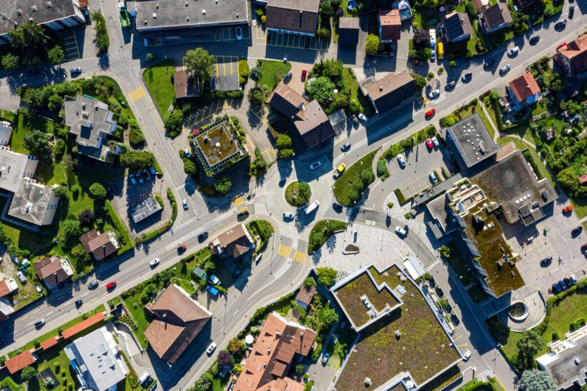 An aerial view of houses surrounding a road featuring a roundabout
