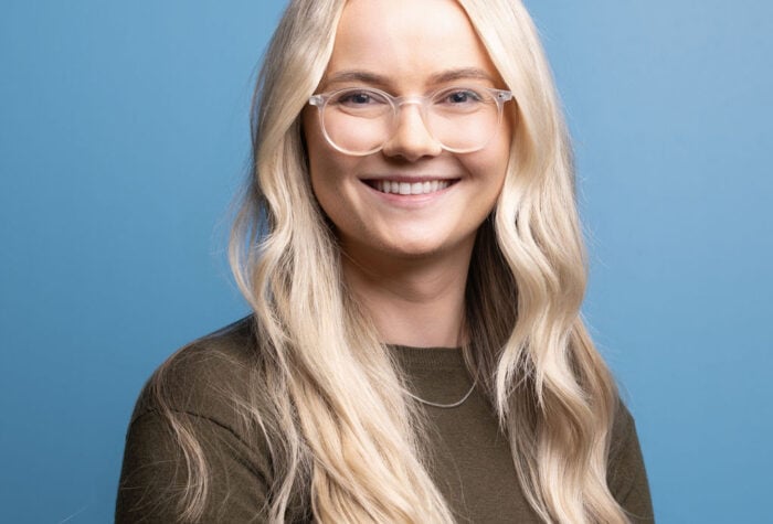 Caroline Gavin a Principal Utilities Consultant at Brookbanks stood in front of a plain blue wall.