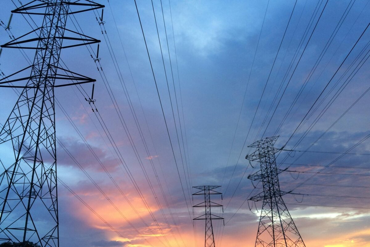 A scenic view of high voltage power lines silhouetted against a vibrant sunset sky.