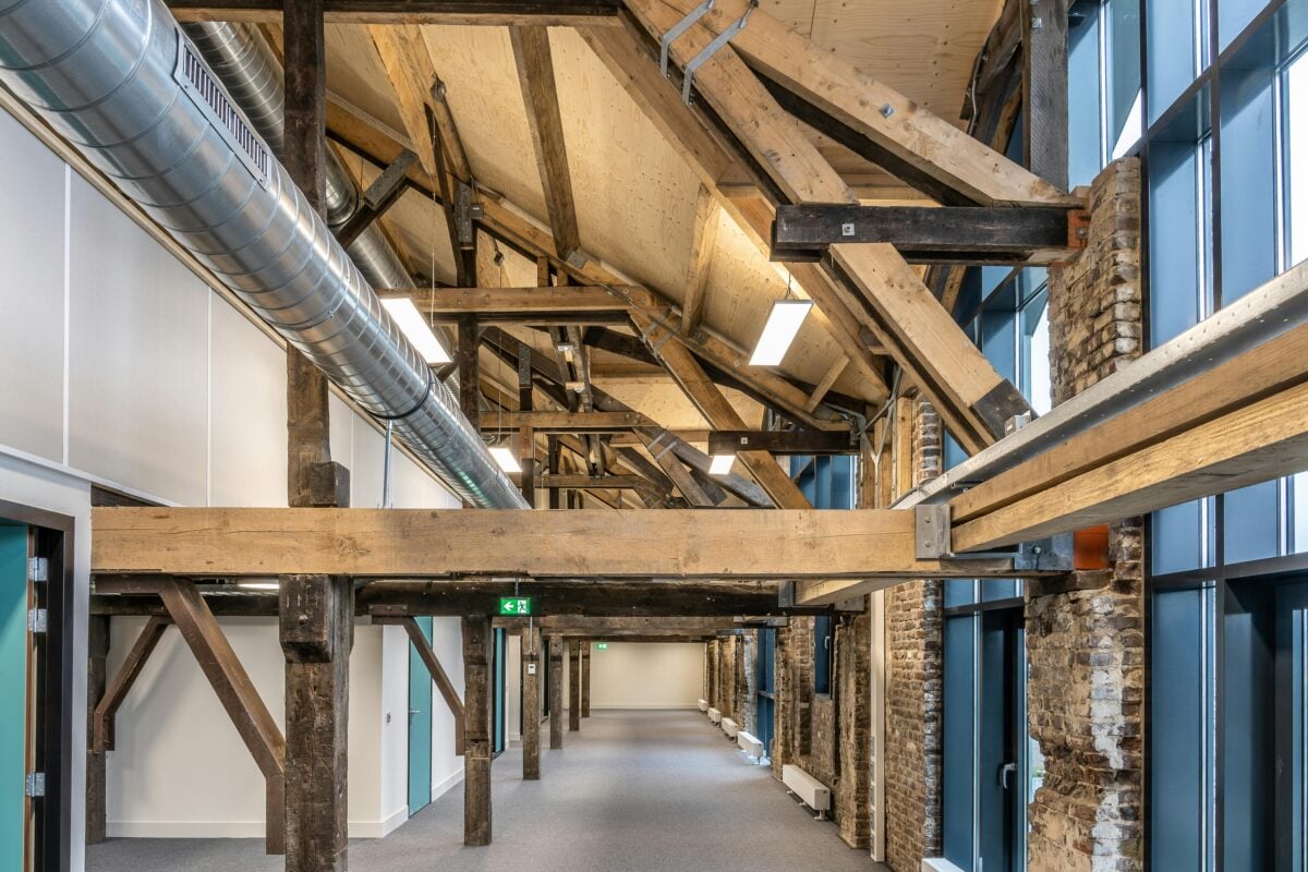 Spacious interior with exposed wooden beams and industrial ductwork, showcasing modern renovation style.