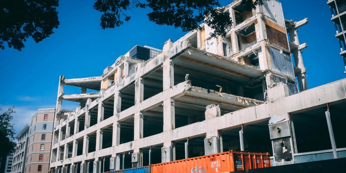 A partially demolished building under clear blue skies, showcasing urban decay and modern architecture.