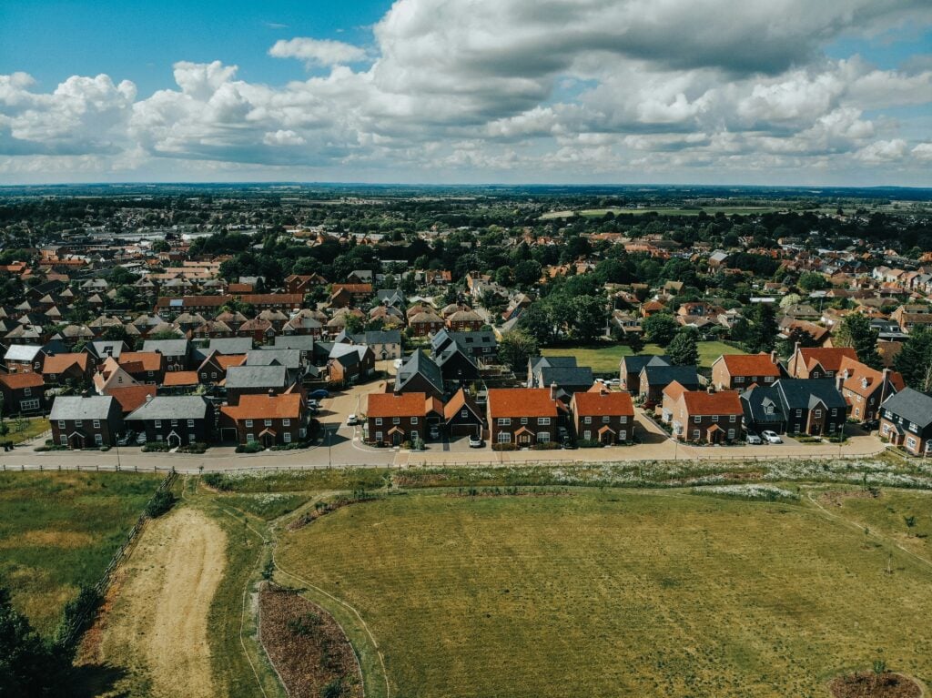 A row of red brick houses behind a field of grass