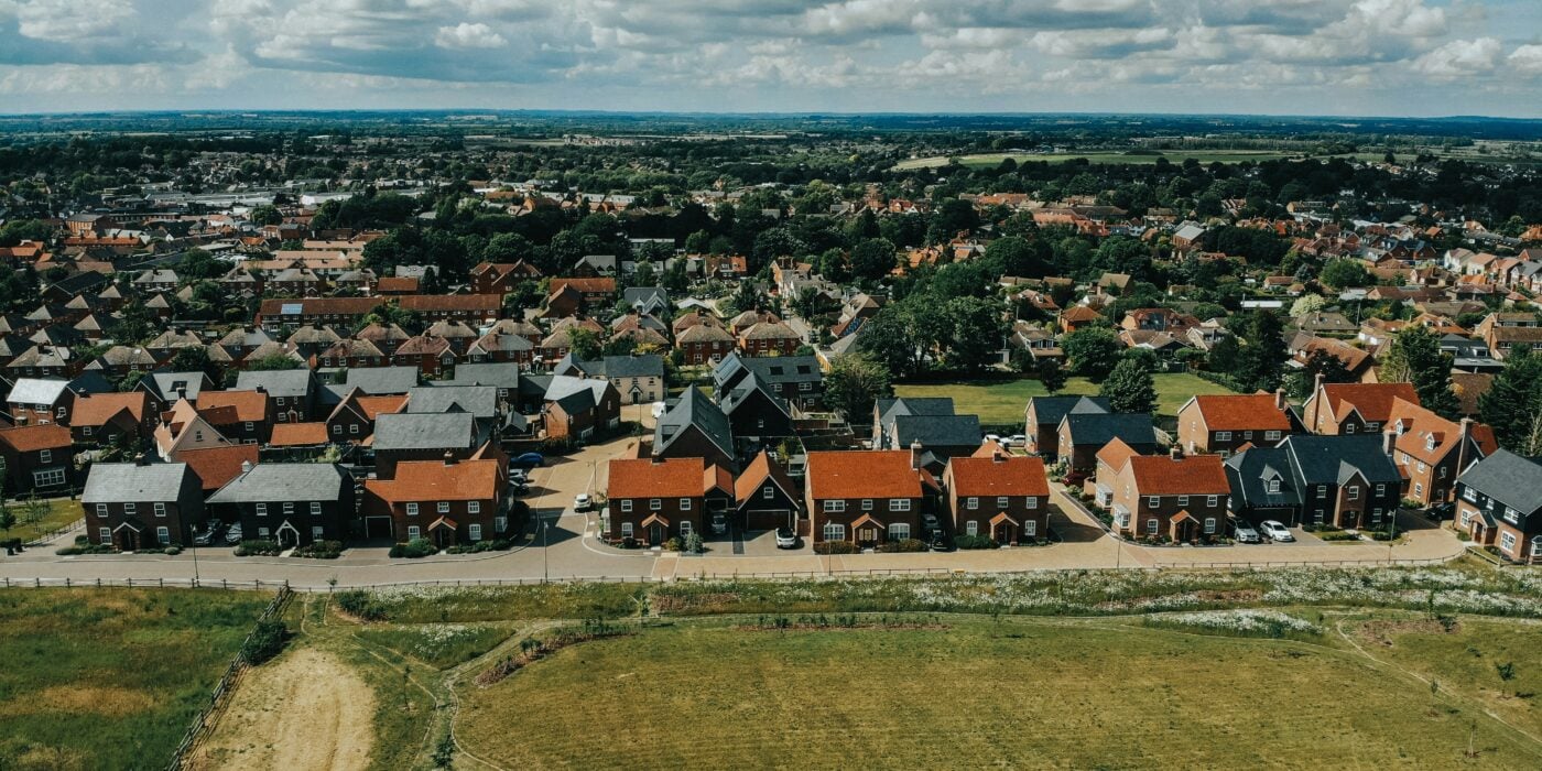 A row of red brick houses behind a field of grass