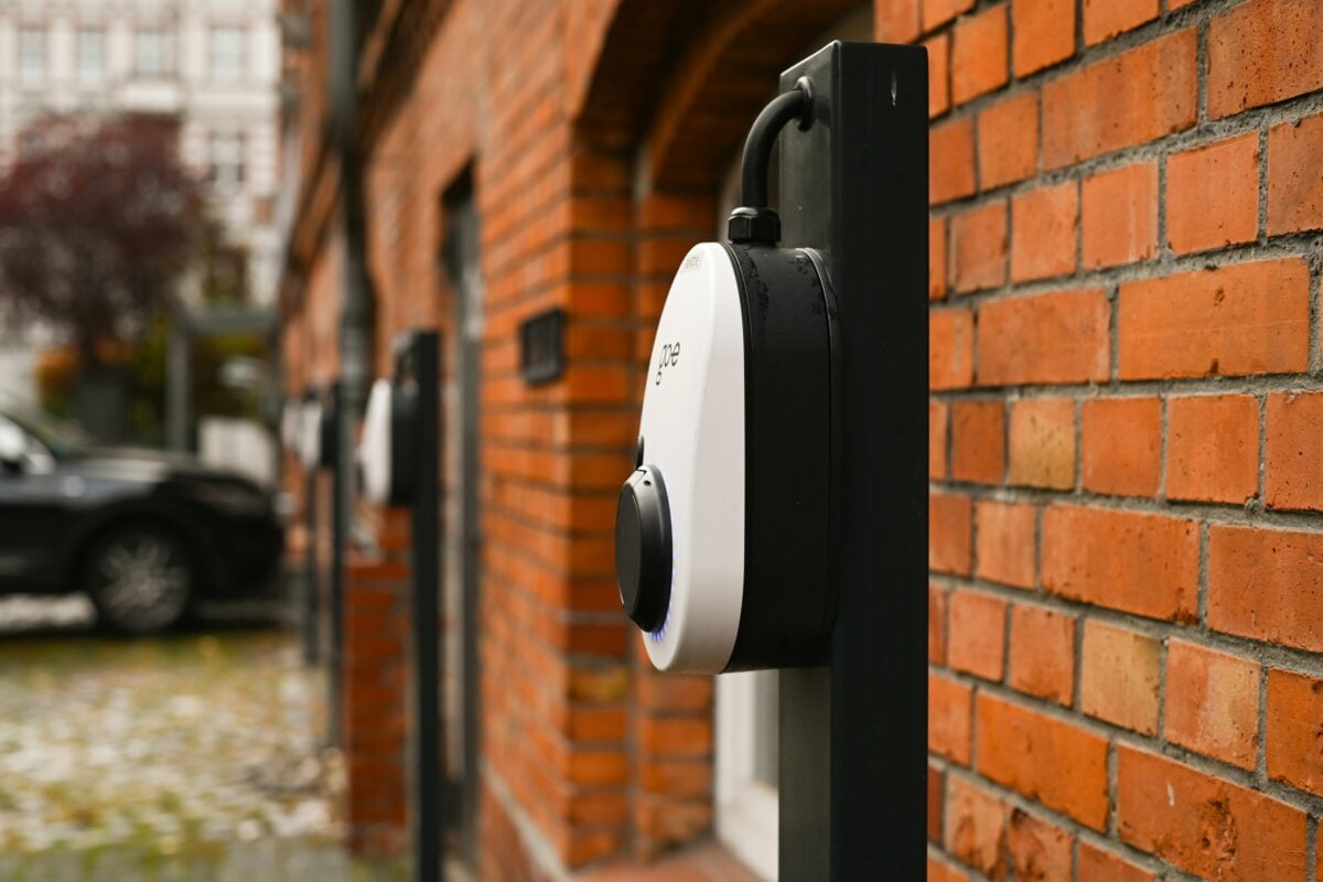 three electric vehicle chargers attached to a red brick wall in an outside car park