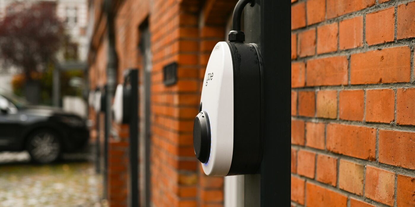 three electric vehicle chargers attached to a red brick wall in an outside car park