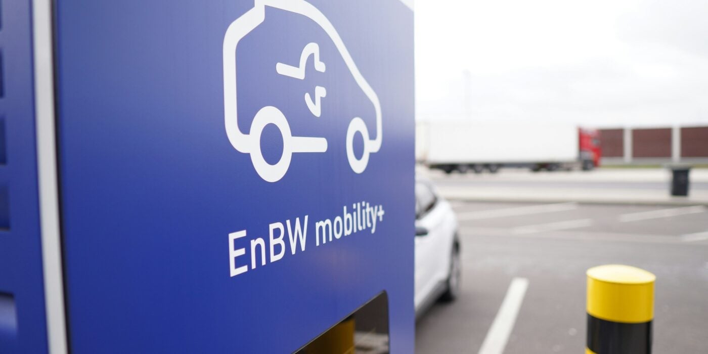 a blue sign in an outdoor car park indicating electric vehicle charging is available
