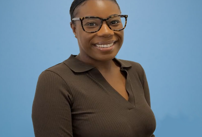 Kimberley Rodney, Accounts Assistant at Brookbanks stood in front of a blue background