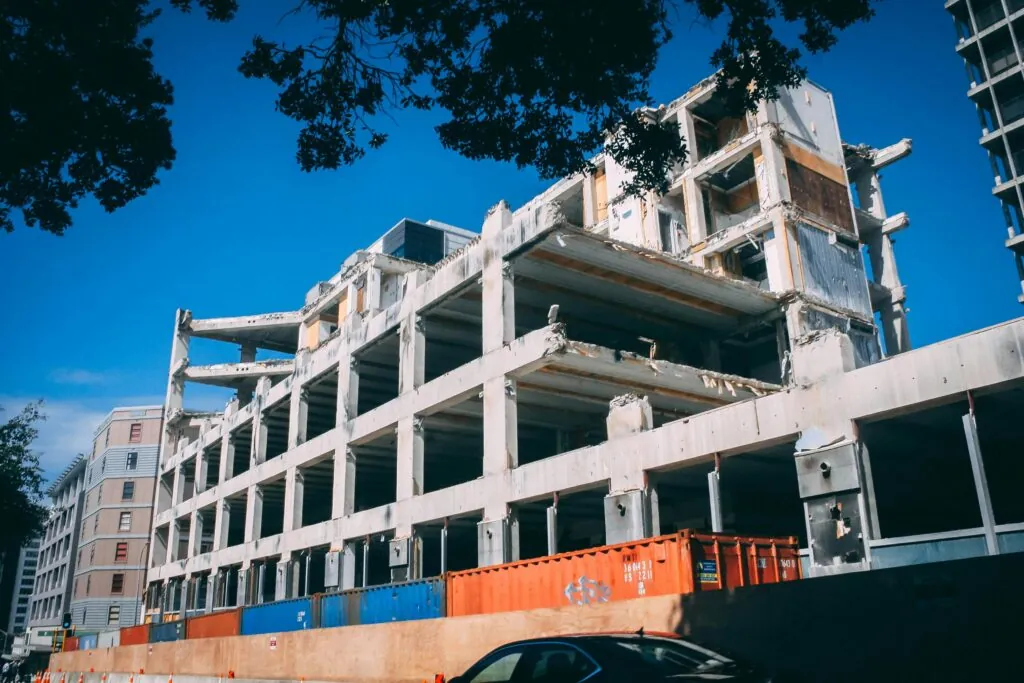 A partially demolished building under clear blue skies, showcasing urban decay and modern architecture.