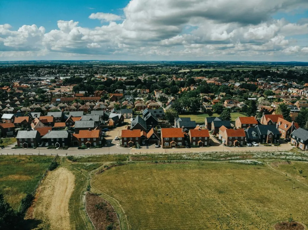 A row of red brick houses behind a field of grass