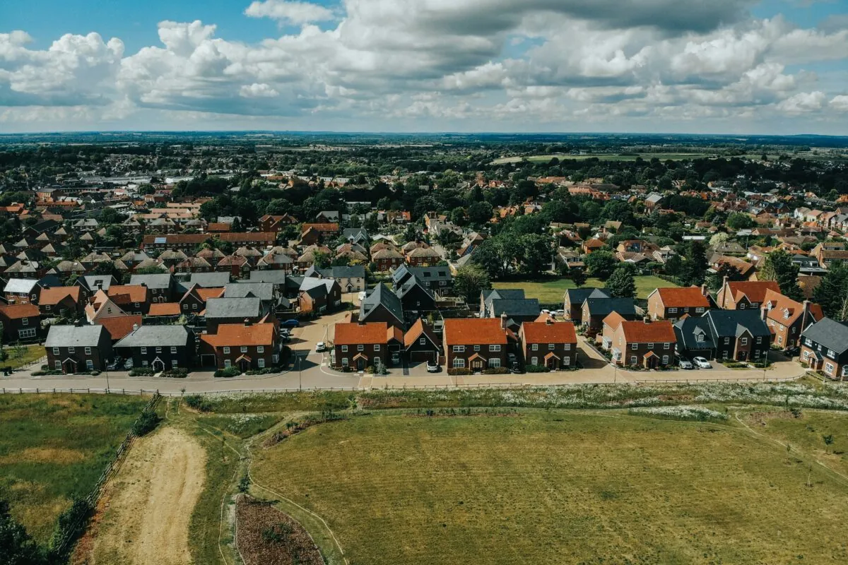 A row of red brick houses behind a field of grass