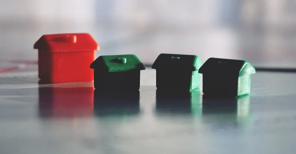 Close-up photo of red and green Monopoly game houses on a reflective surface.