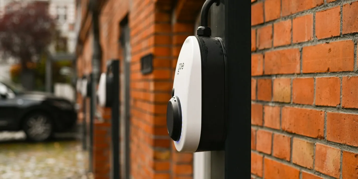 three electric vehicle chargers attached to a red brick wall in an outside car park