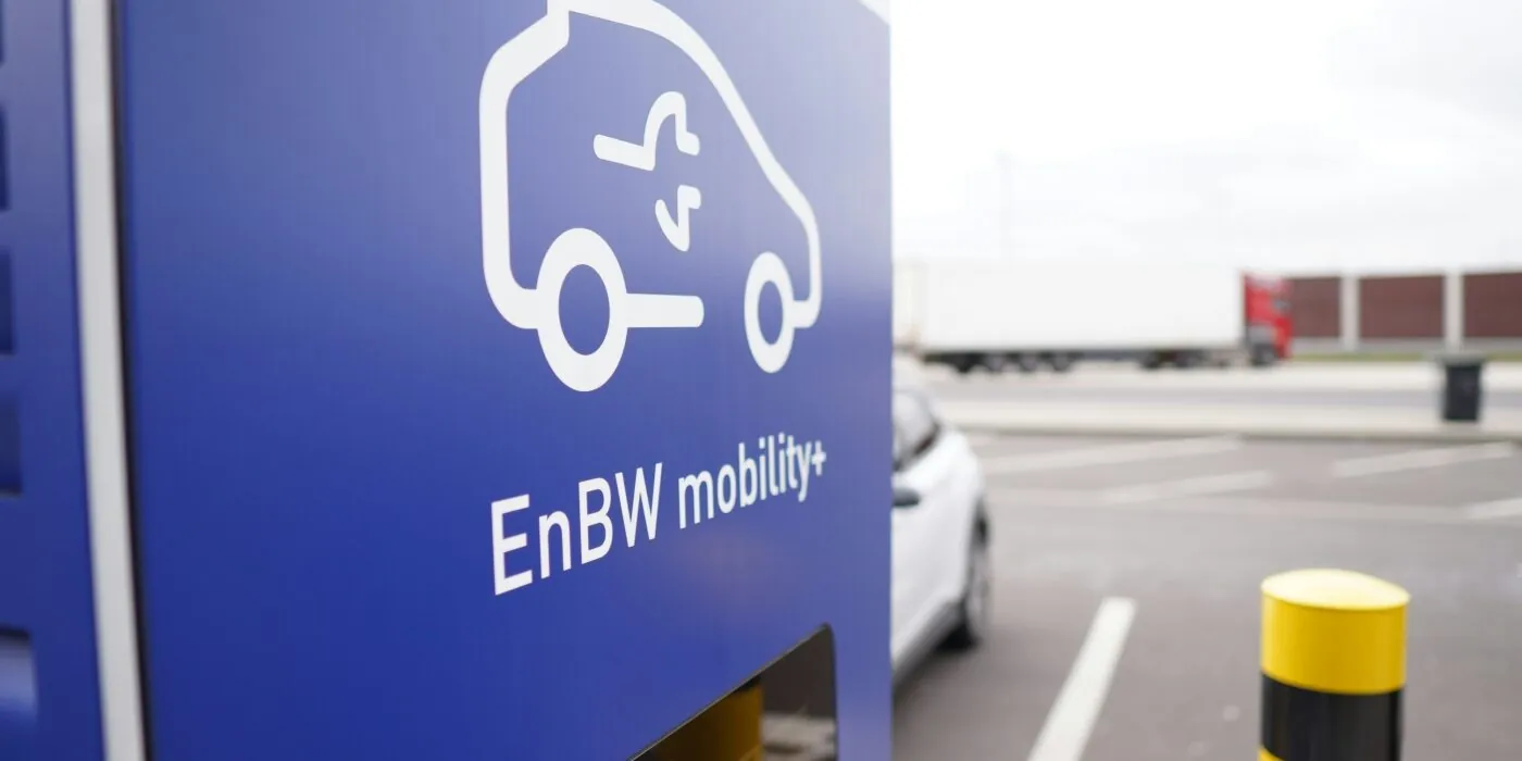 a blue sign in an outdoor car park indicating electric vehicle charging is available