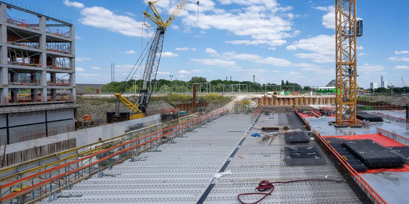 View of a busy construction site with cranes and building structure under clear sky.