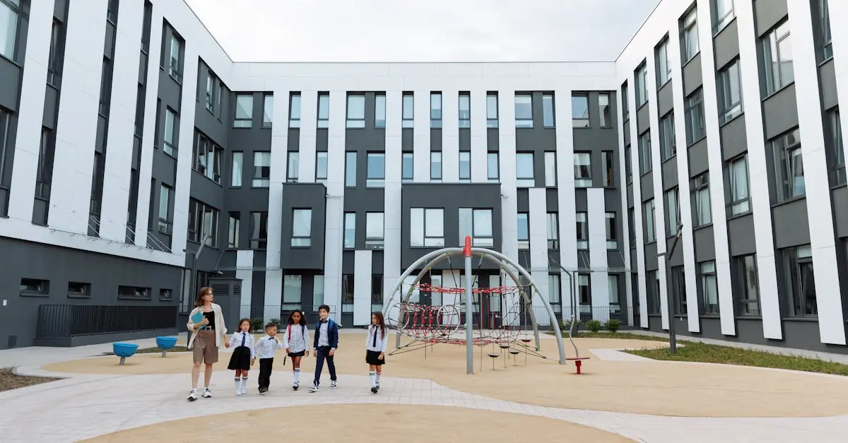 Group of students and teacher walking in a school courtyard with modern architecture and playground.