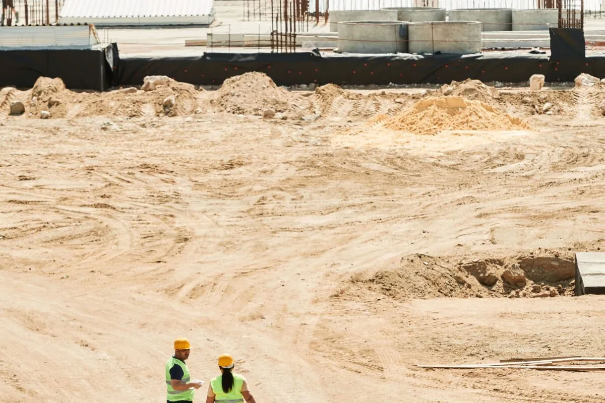 Overhead drone shot of a construction site with two workers in safety gear.